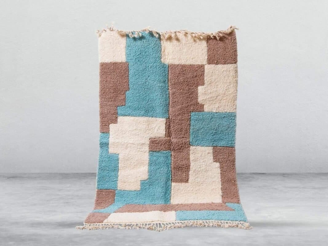 Handwoven Moroccan rug with blue, beige, and brown geometric design.